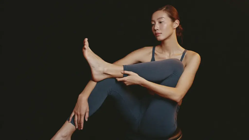 앉은 자세로 발을 들어 발등 위쪽을 손으로 짚어 확인하는 모습, 발등 신전건 부위